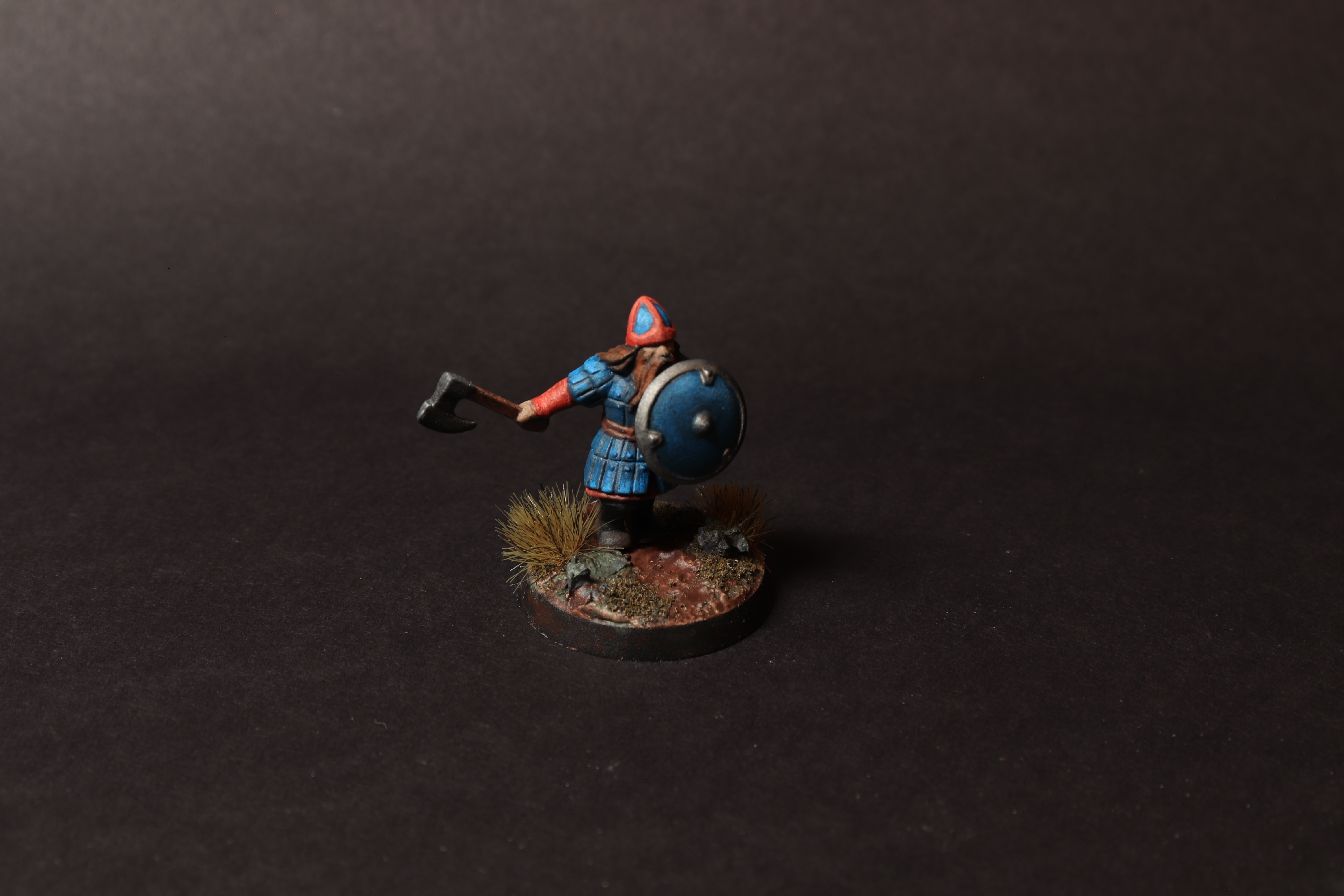 Elevated view of the dwarf warrior miniature showing the shield, helmet, axe, and full scenic base.